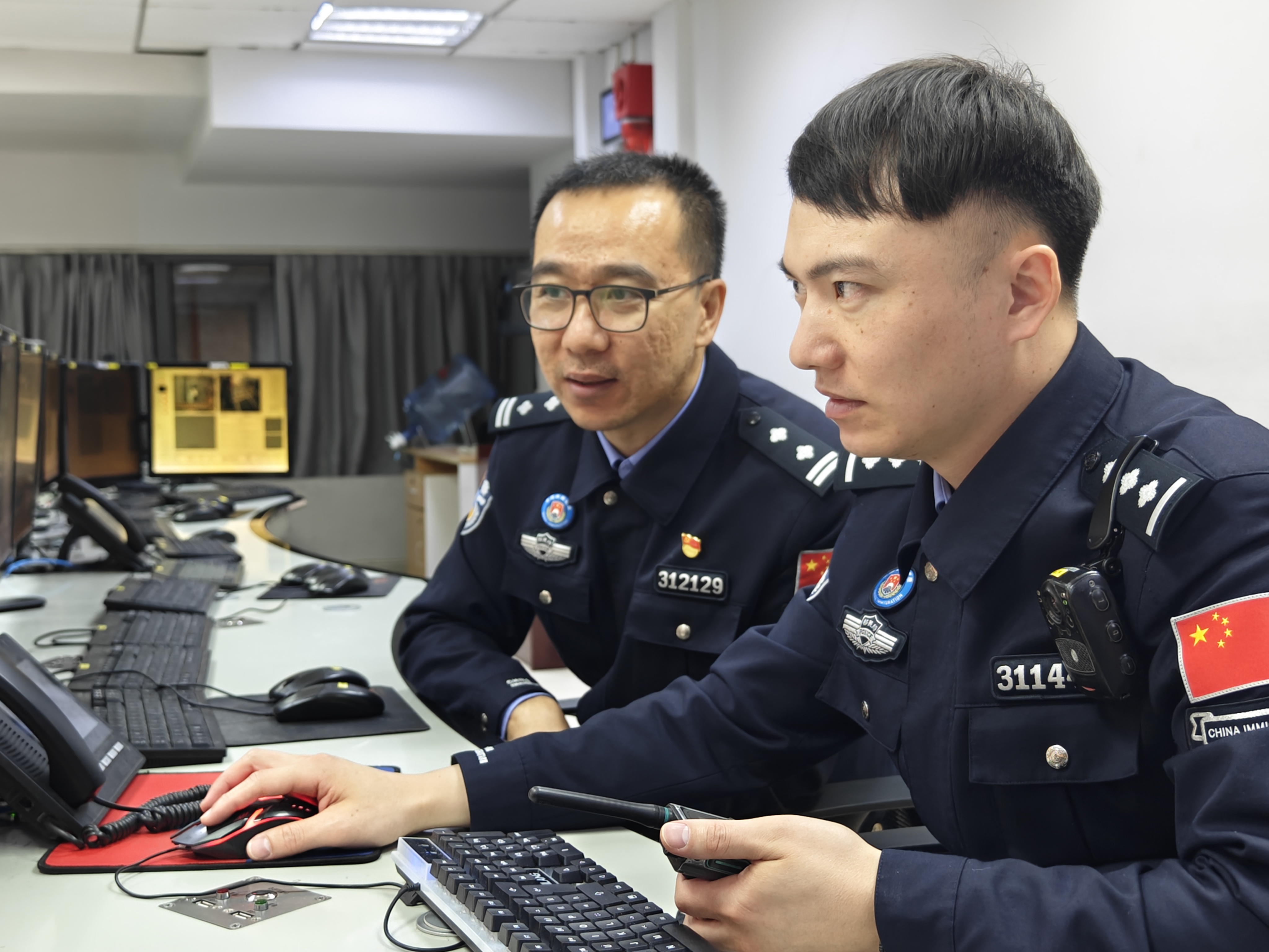 春运进行时,付银鹏(左)向值班民警收集关于边检集中监控系统运行的意见。人民网记者 王雅蝶摄