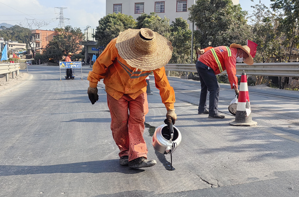 陆川公路养护中心养护工人在国道359线佛山至富宁公路玉林市陆川县沙坡镇路段灌缝。谢倍倩摄