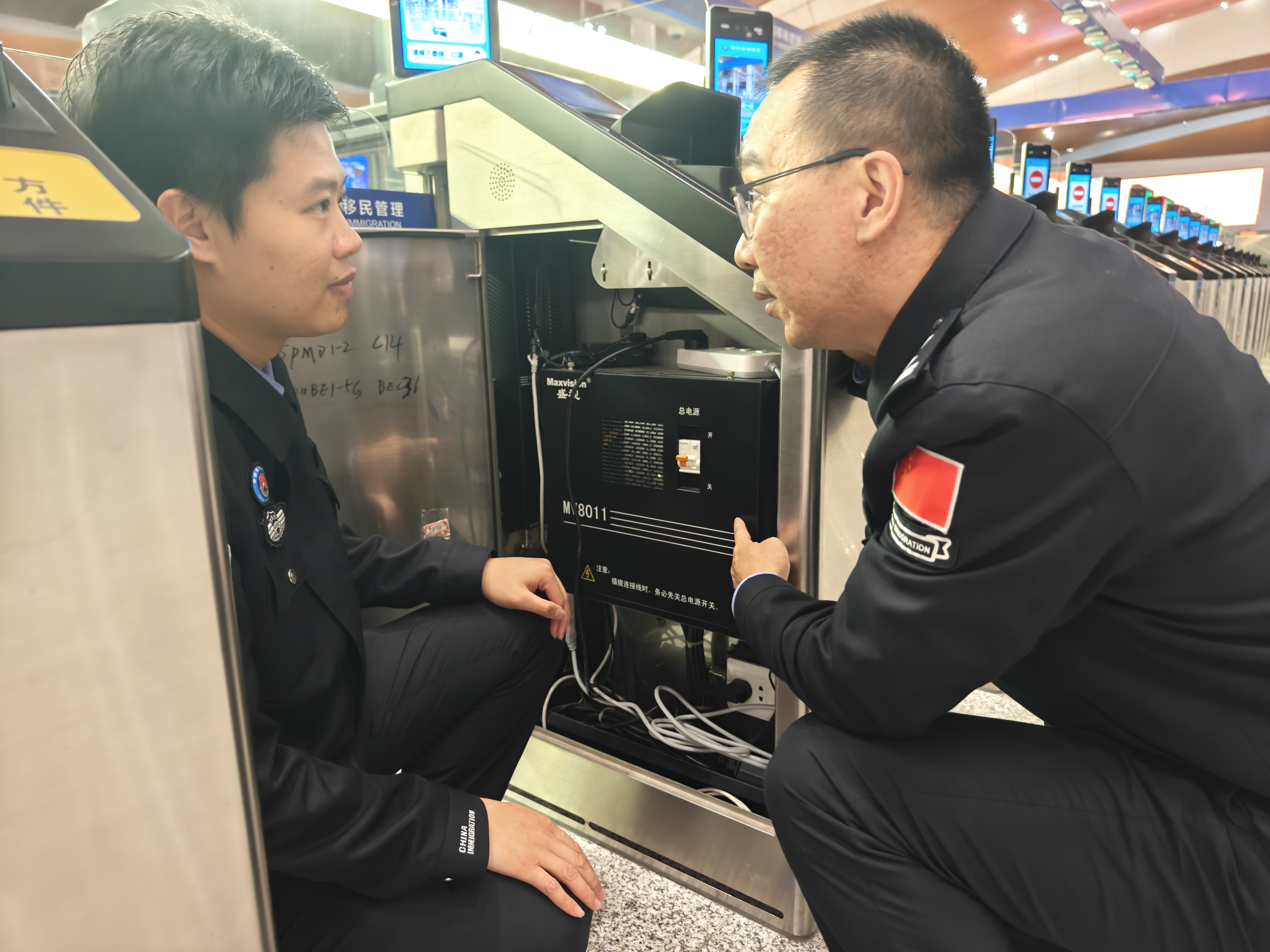 趁客流高峰过去,付银鹏(右)和同事检查通关设备电池运行情况。人民网记者 王雅蝶摄